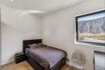 Discover the tranquility of this modern bedroom, featuring a comfortable bed and a stunning mountain view from the large window.