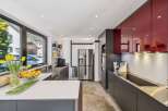 This modern kitchen boasts sleek, dark cabinetry and striking red upper cabinets, creating a sophisticated contrast.