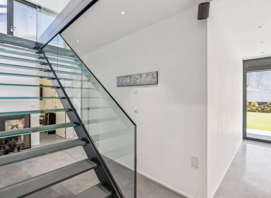 This stunning property boasts a modern interior with a sleek glass staircase, creating an open and airy feel.