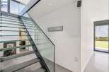 This stunning property boasts a modern interior with a sleek glass staircase, creating an open and airy feel.