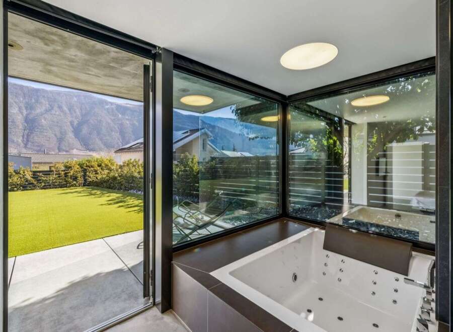 Indulge in luxury with this stunning property featuring a modern bathroom with a jacuzzi and expansive windows.
