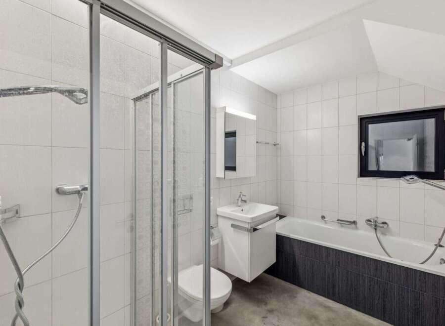 This modern bathroom boasts a sleek design with white tiled walls and a glass shower enclosure.
