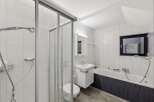 This modern bathroom boasts a sleek design with white tiled walls and a glass shower enclosure.