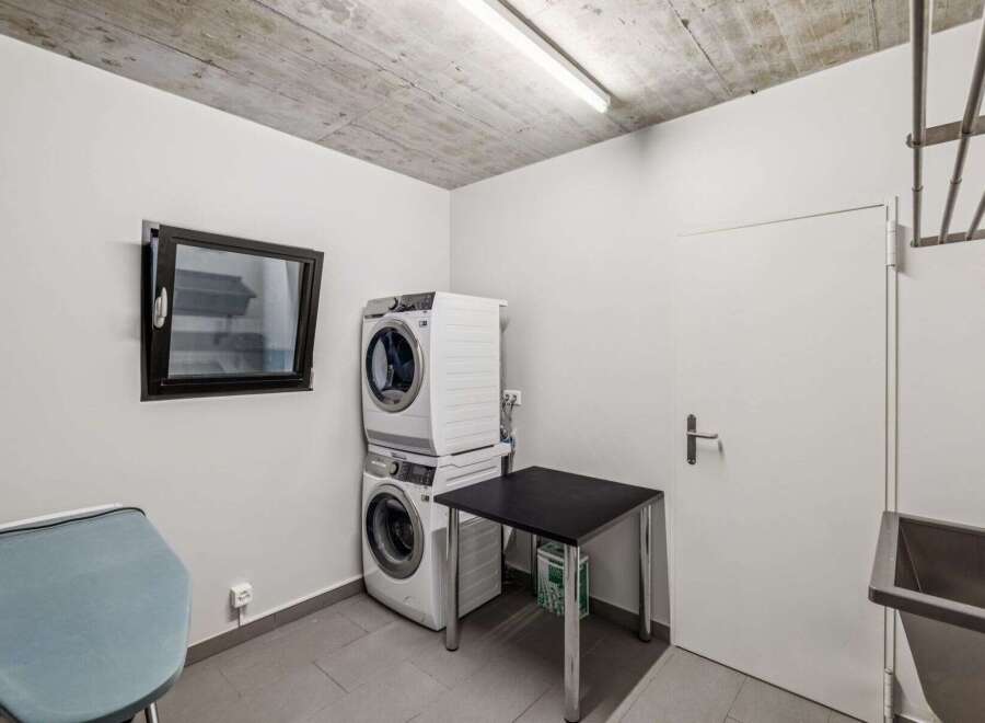 Discover the convenience of this well-equipped laundry room! Featuring a modern stacked washer and dryer, this space is designed for efficiency.