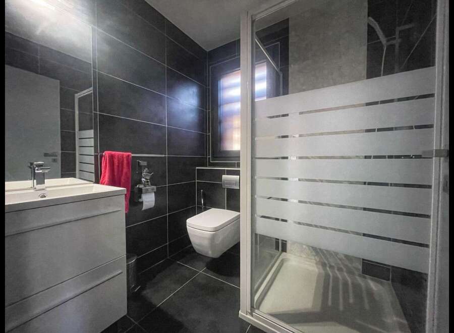 Step into this modern bathroom, featuring sleek black tiles and a contemporary design.