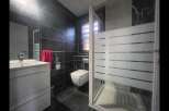 Step into this modern bathroom, featuring sleek black tiles and a contemporary design.