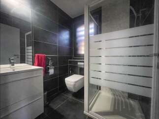 Step into this modern bathroom, featuring sleek black tiles and a contemporary design.