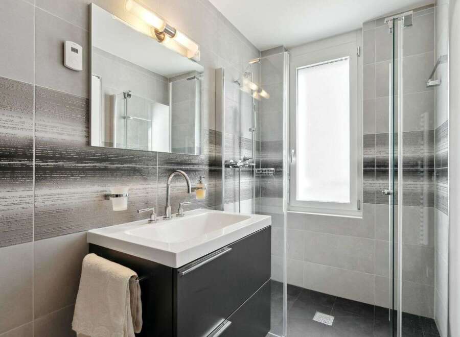 This modern bathroom features a sleek design with a dark gray vanity and a white sink.