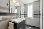 This modern bathroom features a sleek design with a dark gray vanity and a white sink.