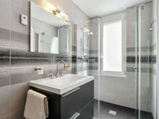 This modern bathroom features a sleek design with a dark gray vanity and a white sink.