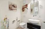 This modern bathroom features a sleek design with a floating toilet and a stylish vessel sink.