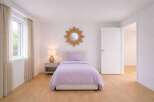 This inviting bedroom features a cozy single bed with a soft lavender comforter, creating a serene atmosphere.