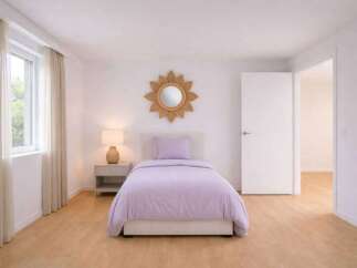This inviting bedroom features a cozy single bed with a soft lavender comforter, creating a serene atmosphere.