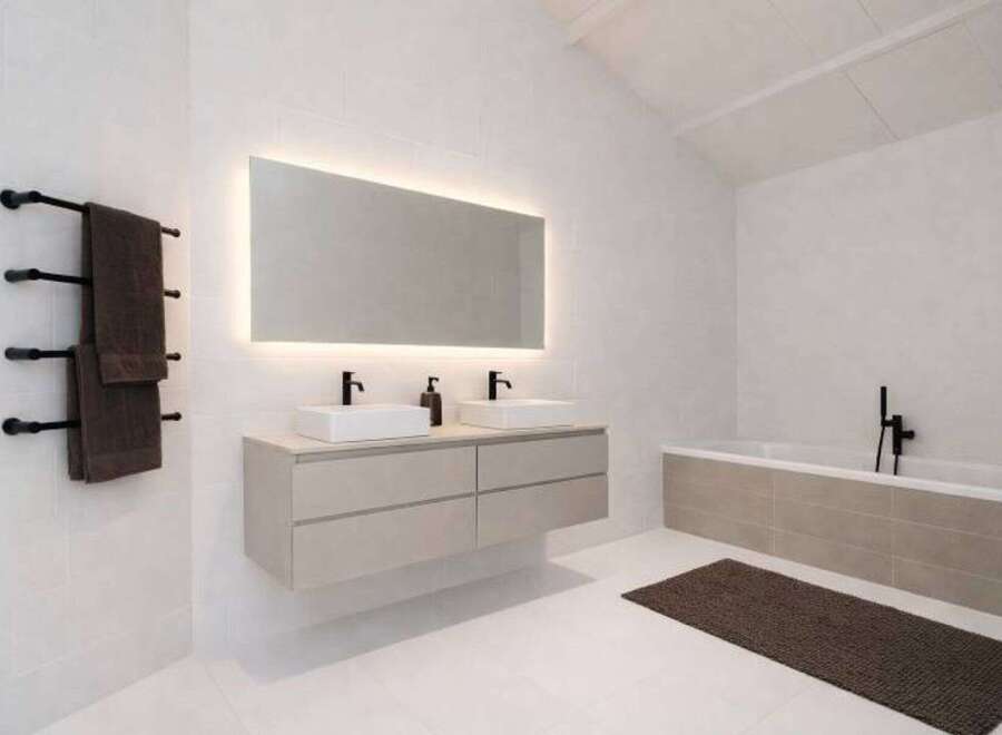 This modern bathroom boasts a sleek design with a floating vanity and a large illuminated mirror.