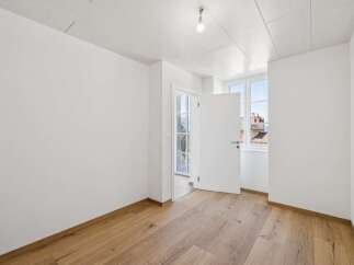 Experience modern living in this bright and airy room featuring pristine white walls and a beautiful light wood floor.