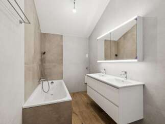 Experience modern luxury in this stunning bathroom featuring a sleek double vanity with integrated lighting and a spacious bathtub perfect for relaxation.