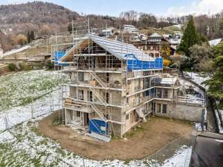 This multi-story residential building is currently under construction, featuring a stone facade and extensive scaffolding.