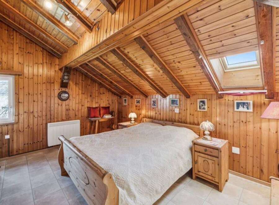 Step into a cozy retreat with this charming bedroom, featuring warm wooden paneling and a unique sloped ceiling.