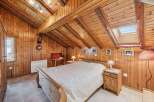 Step into a cozy retreat with this charming bedroom, featuring warm wooden paneling and a unique sloped ceiling.
