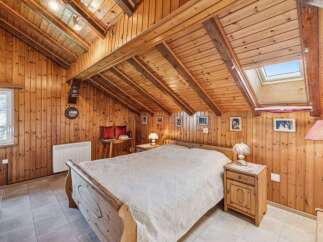 Step into a cozy retreat with this charming bedroom, featuring warm wooden paneling and a unique sloped ceiling.