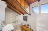 This charming bathroom features a unique sloped wooden ceiling, adding character and warmth to the space.