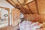 This charming bedroom boasts a rustic aesthetic with its wooden ceiling and walls, creating a warm and inviting atmosphere.
