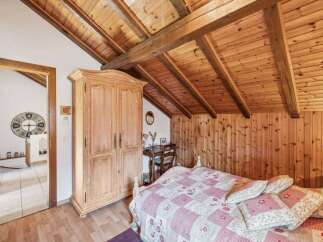 This charming bedroom boasts a rustic aesthetic with its wooden ceiling and walls, creating a warm and inviting atmosphere.