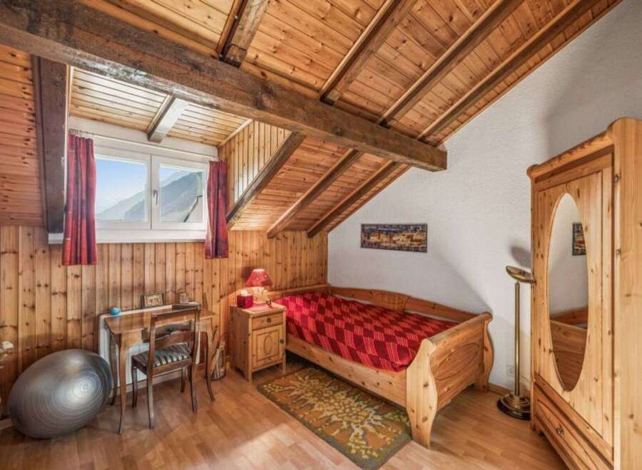 Discover the charm of this cozy bedroom featuring a unique wooden ceiling and walls, creating a warm and inviting atmosphere.
