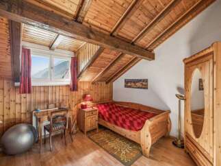 Discover the charm of this cozy bedroom featuring a unique wooden ceiling and walls, creating a warm and inviting atmosphere.