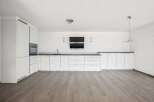 This modern kitchen boasts sleek white cabinetry, offering ample storage and a clean aesthetic.