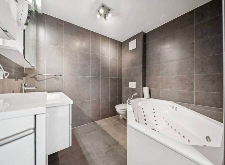 This modern bathroom features a sleek design with gray tiled walls and flooring, creating a sophisticated ambiance.
