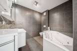 This modern bathroom features a sleek design with gray tiled walls and flooring, creating a sophisticated ambiance.