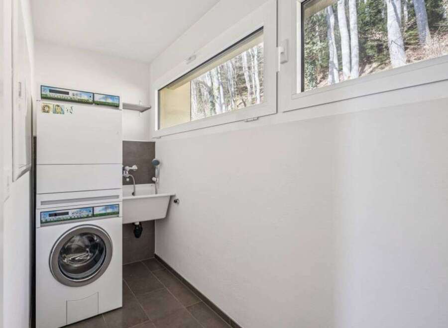 This laundry room features a modern design with a washing machine and a sink.