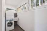 This laundry room features a modern design with a washing machine and a sink.
