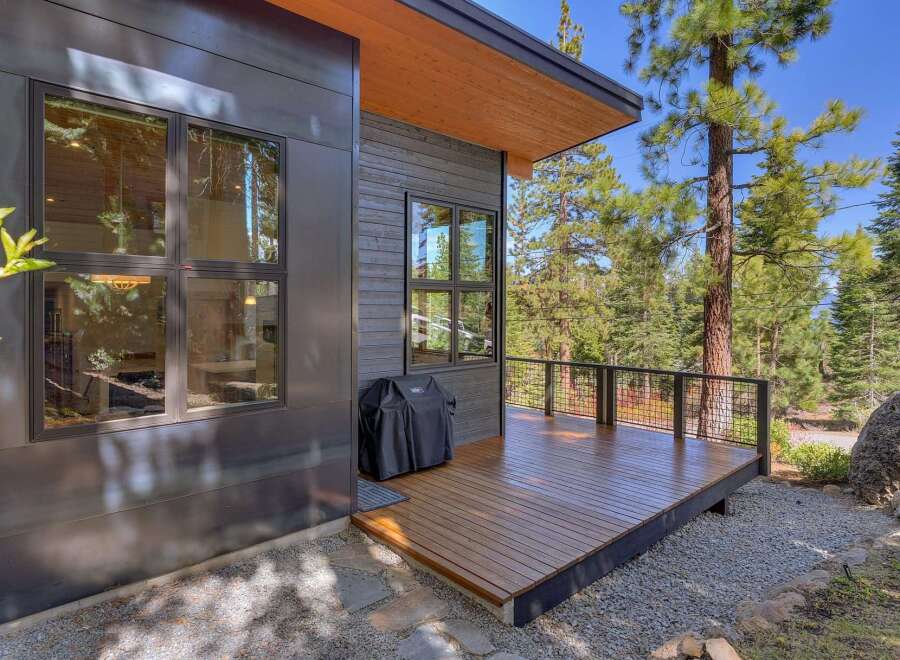This stunning property boasts modern architecture with sleek lines and a beautiful wooden deck, perfect for outdoor entertaining.