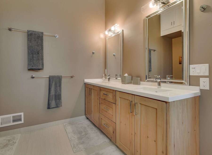 This stunning bathroom features a modern design with a natural wood vanity and a sleek white countertop.