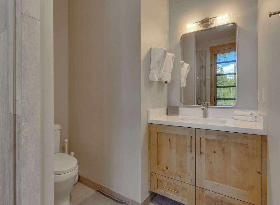 This stunning bathroom features a modern design with natural wood cabinetry and a sleek white countertop.