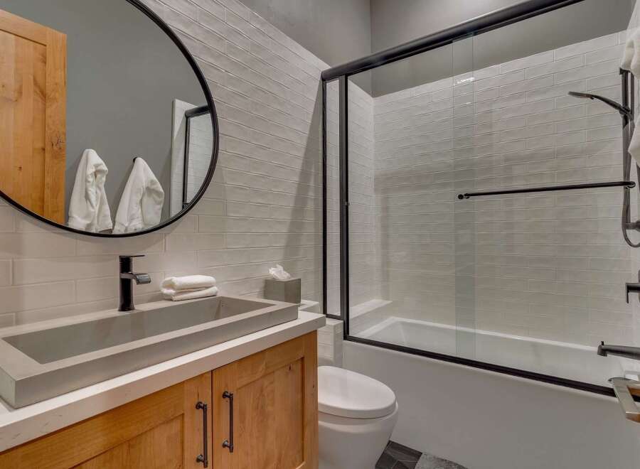 This modern bathroom features a sleek design with a concrete sink and wooden cabinetry.