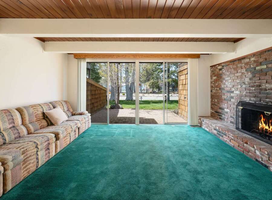 Step into this inviting living space, featuring a cozy fireplace and a vibrant green carpet.