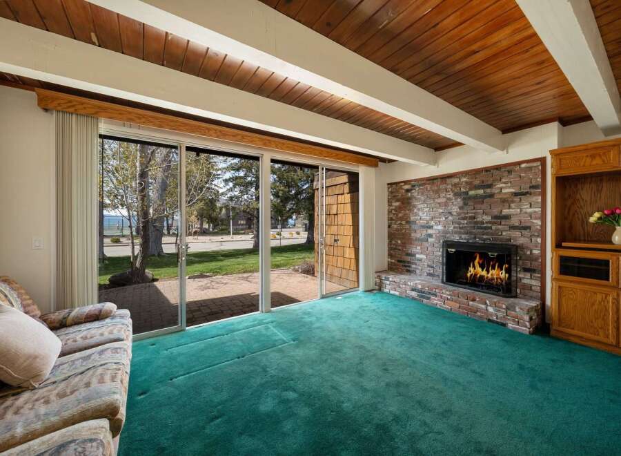 Step into this inviting living space, featuring a cozy brick fireplace and a vibrant green carpet that adds a touch of warmth.