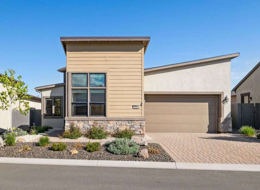 This stunning modern home boasts a beautiful exterior with a combination of stone and siding.
