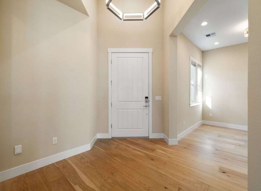 Step into this stunning entryway, showcasing beautiful hardwood floors and a modern, geometric light fixture.