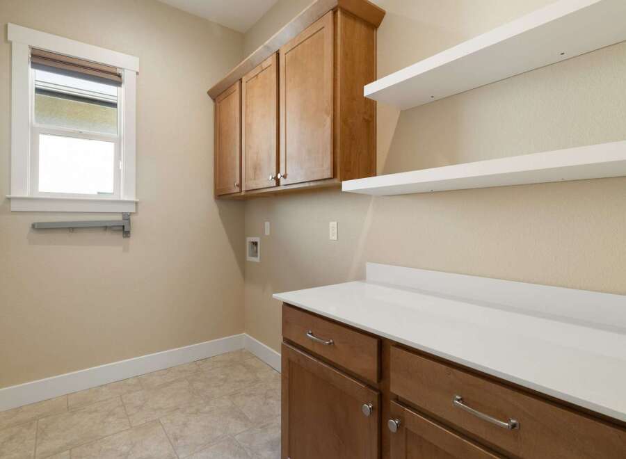 This stunning laundry room boasts ample storage with its custom cabinetry and floating shelves, perfect for organizing all your essentials.