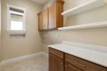 This stunning laundry room boasts ample storage with its custom cabinetry and floating shelves, perfect for organizing all your essentials.