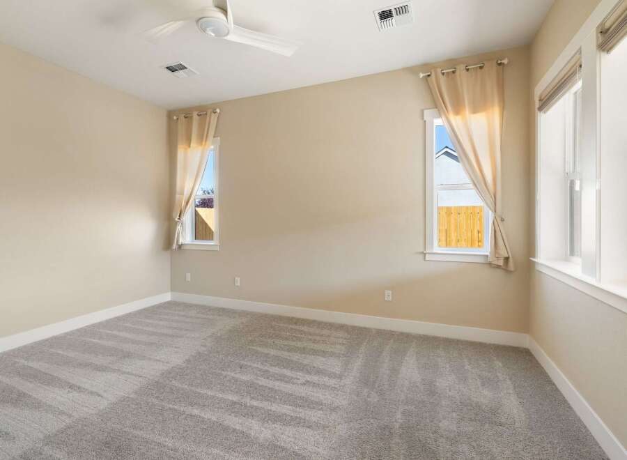 This inviting bedroom boasts a neutral color palette and ample natural light, creating a serene atmosphere.