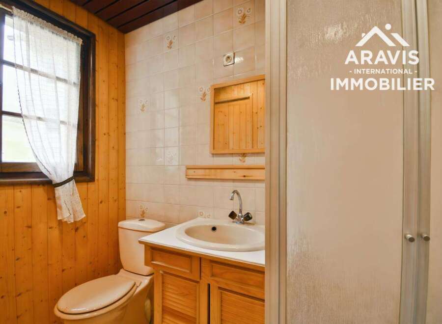 Discover this charming bathroom featuring a cozy wooden interior and a bright window.