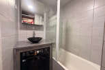 Discover this modern bathroom featuring a sleek black washing machine and a stylish vessel sink.