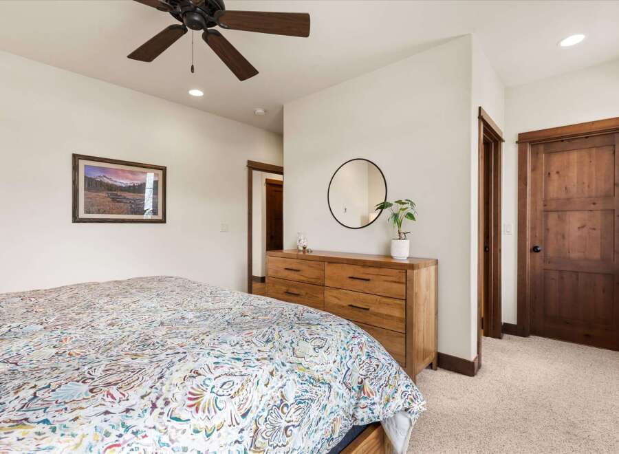 Step into this inviting bedroom, featuring a stylish ceiling fan and a cozy bed adorned with a colorful comforter.