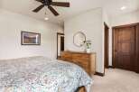 Step into this inviting bedroom, featuring a stylish ceiling fan and a cozy bed adorned with a colorful comforter.