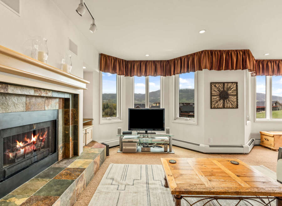 This stunning living room boasts a cozy fireplace with a stone surround, perfect for those chilly evenings.
